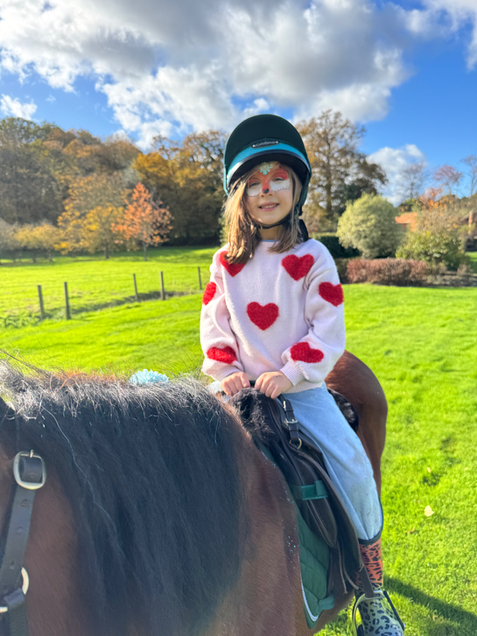 Girl with face paint and helmet riding horse