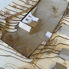 Architectural model of a white building within a contoured landscape.