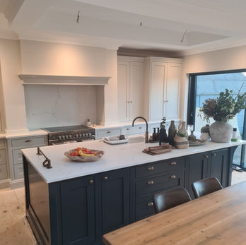 Spacious modern kitchen with large dark island, light countertops, and wood table.