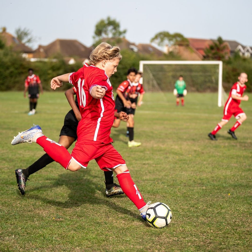 Young soccer player kicks the ball during a daytime match on the field