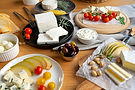 Assortment of cheeses, cherry tomatoes, sliced pears, olives, and nuts on a table.