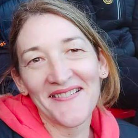 Smiling woman in red holding a warm sweater, looking directly at the camera