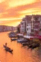 Venice canal with gondolas and buildings at sunset with golden sky