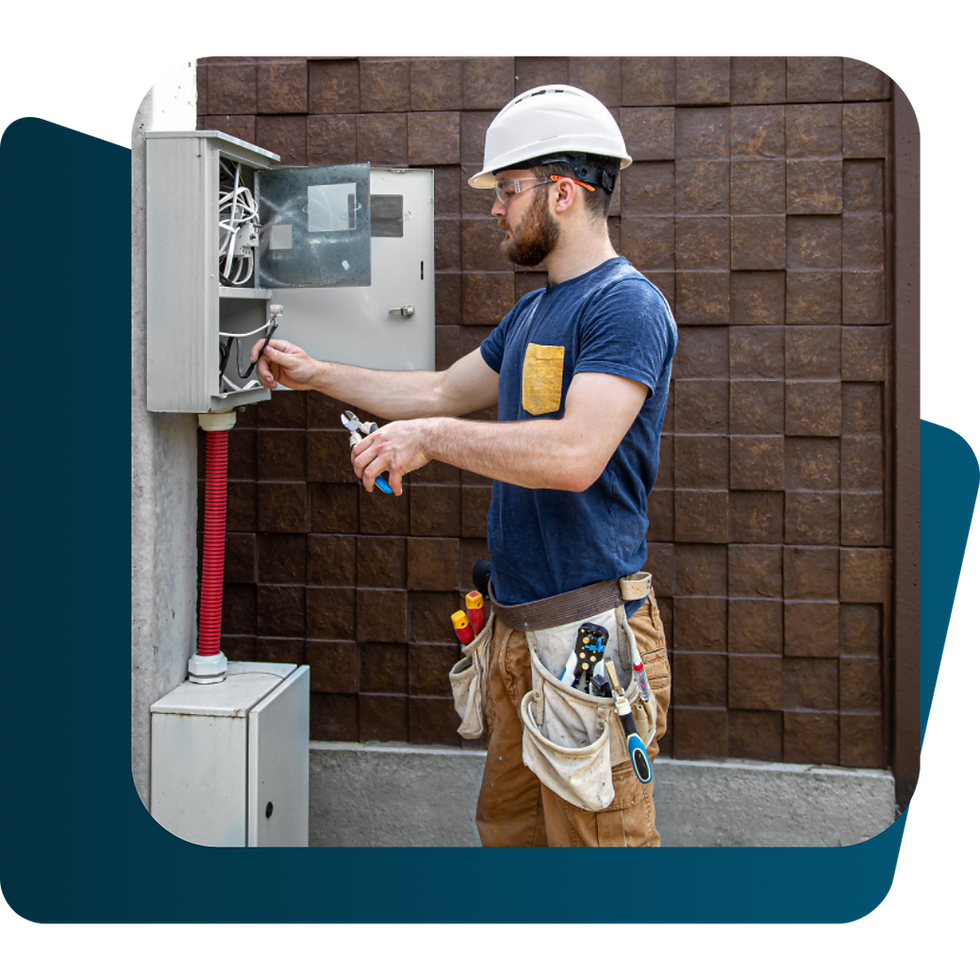 Electrician in hard hat working on outdoor power box, using tools