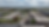 Aerial view of buildings, cars, and trees under a cloudy sky.