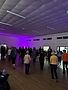 People dancing in a large hall with purple ambient lighting.