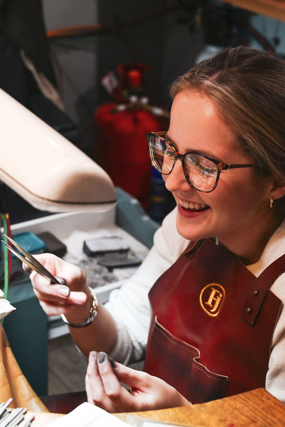 Jeweler in leather apron working at her bench