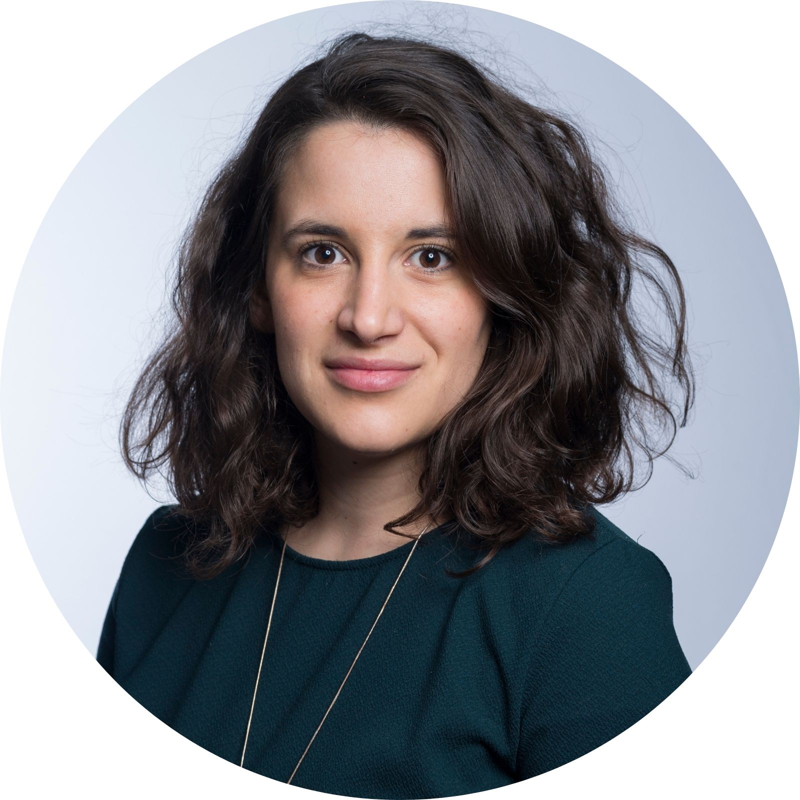 Young woman with dark curly hair smiling in professional headshot.