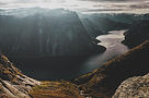 Deep fjord cutting through rocky mountains under a cloudy sky