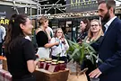 People talking at a market with jars of food on display