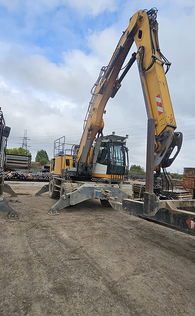 A large yellow excavator on a construction site under a cloudy sky.