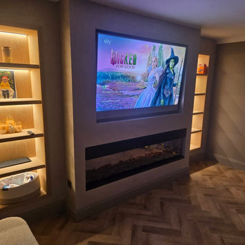 Modern living room with large TV, electric fireplace, and backlit shelving.