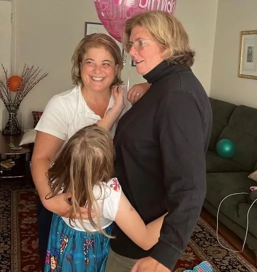 Happy women embracing with a child, celebrating with a 'mommy' balloon.