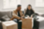 Diverse couple packing cardboard boxes on a gray couch.