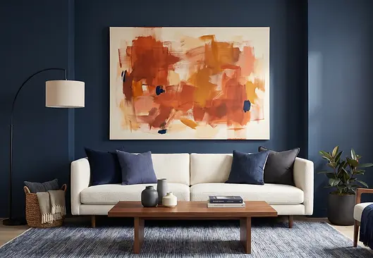 Burnt orange and terracotta abstract gallery-wrapped canvas art displayed on a deep navy living room wall, demonstrating blue-orange complementary color contrast that creates a bold visual focal point.