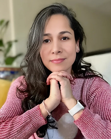 Judith Flores-Nisenson seated with hands under chin, offering a calm, supportive expression as a Certified Life Coach.