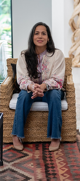 udith Flores-Nisenson seated comfortably on a woven bench, creating a grounded and welcoming presence.