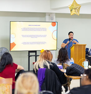 Black women in blue dress standing at a Power Point screen in front of an audience.