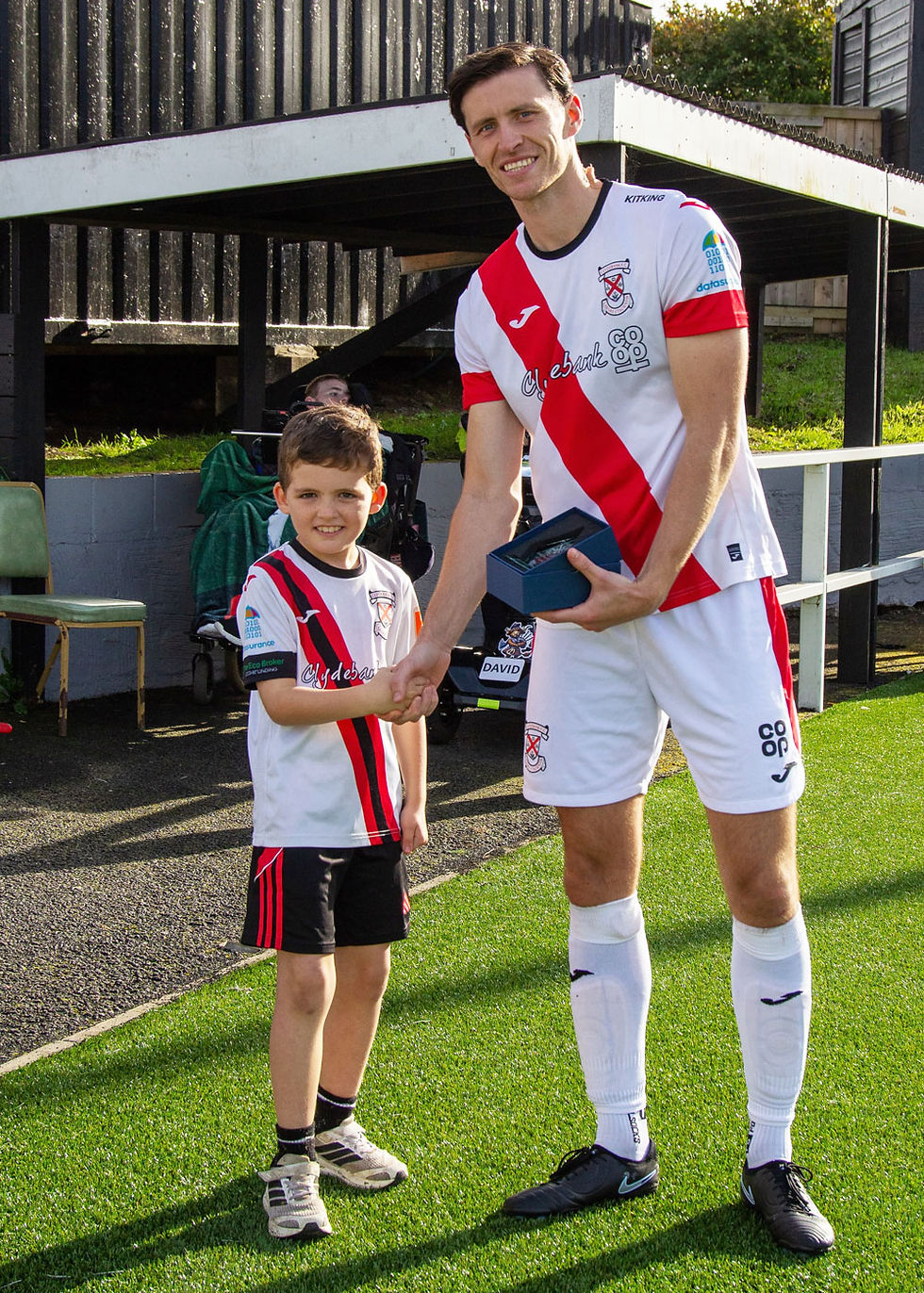 Young CAG volunteer fundraiser presents a trophy to player Matt Niven to celebrate his 150th appearance!