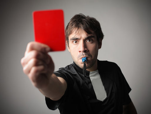 Referee blowing a whistle and showing a red card, symbolising disciplinary action, rule enforcement, and the escalation of charges in workplace misconduct cases.