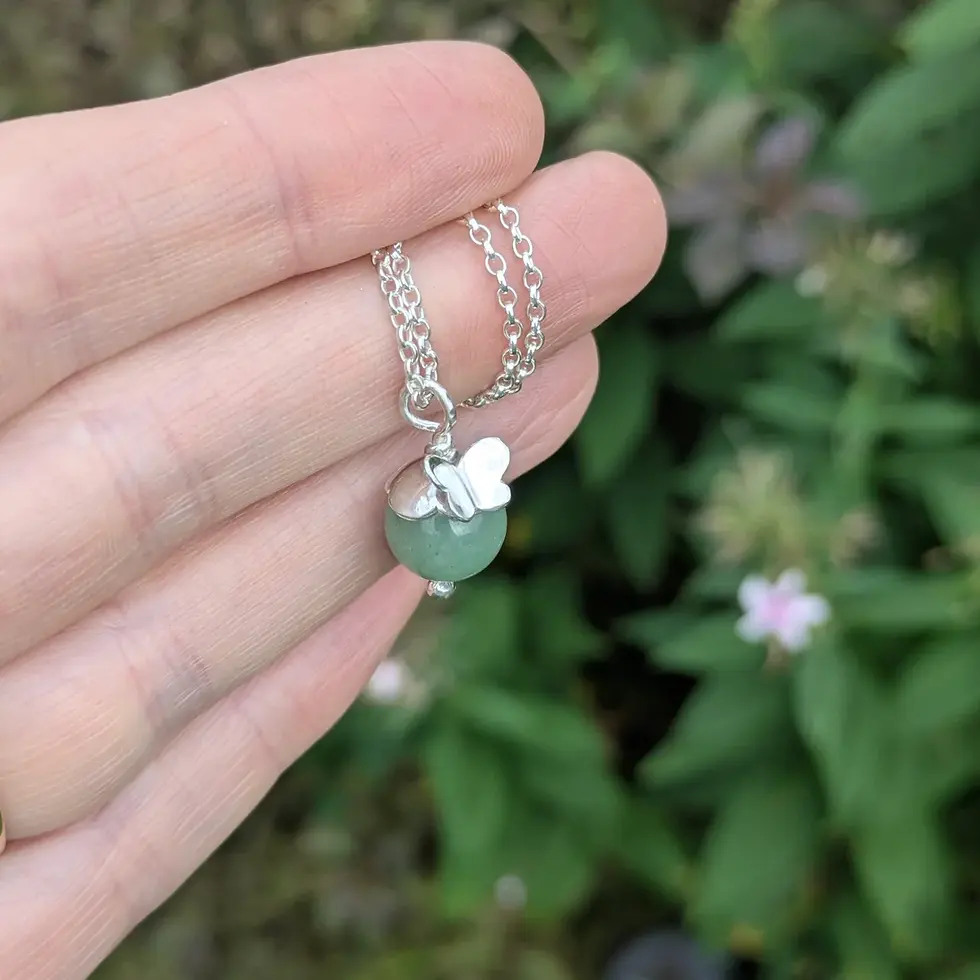 aventurine and butterfly necklace lying on a hand