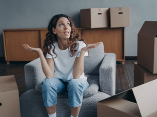 Woman sitting among moving boxes and considering her options for a long-distance move.