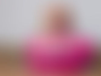 A beagle dog wearing sunglasses and a Hawaiian flower lei resting on a pink suitcase, representing moving to Hawaii with a dog or cat.