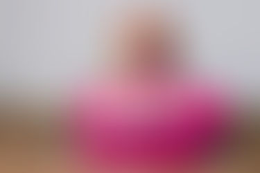 A beagle dog wearing sunglasses and a Hawaiian flower lei resting on a pink suitcase, representing moving to Hawaii with a dog or cat.