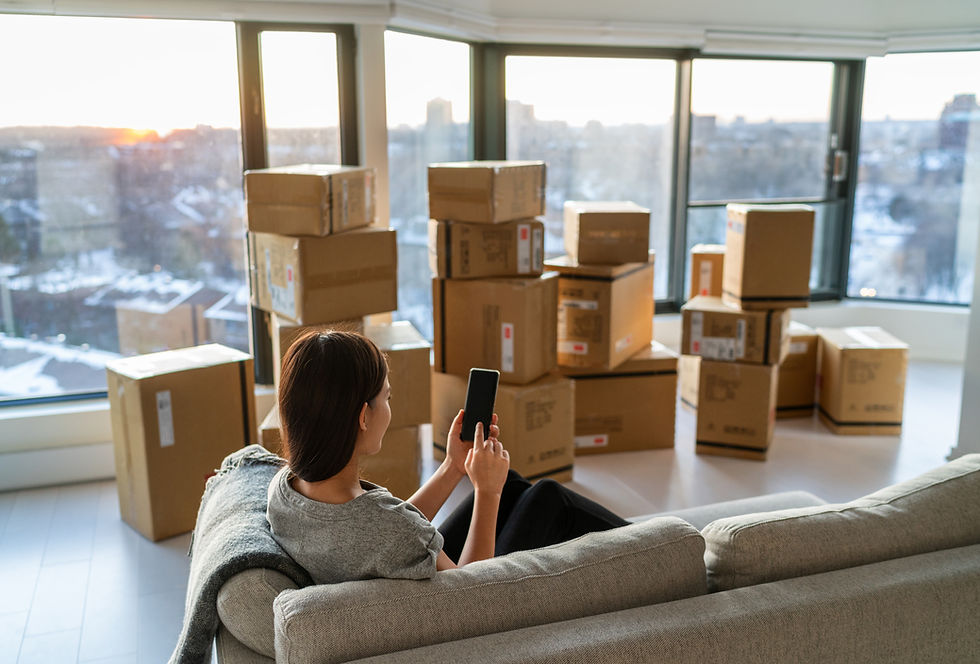 Woman relaxing with a phone in a living room filled with packed cardboard boxes during a local residential move