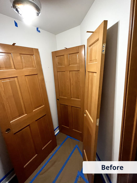 Before photo of hallway with wooden doors and taped flooring, prepping for white door painting