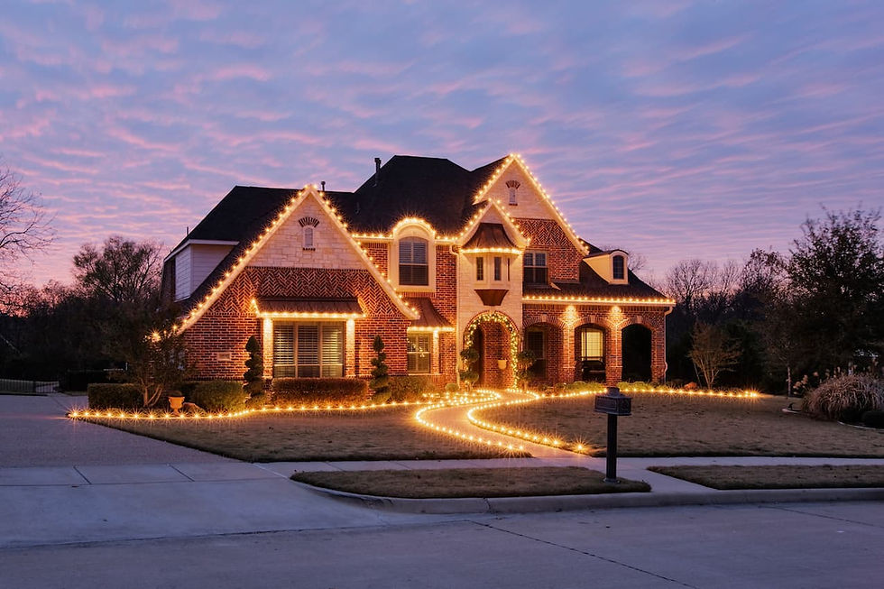 Outdoor Christmas light installation on a brick suburban house with roofline and pathway lighting at sunset.