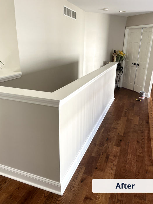 After photo of a freshly painted stair landing area with white wainscoting and neutral walls
