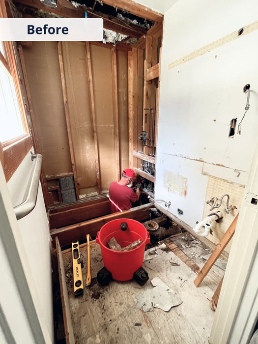 Bathroom before renovation — exposed framing, old plumbing, and partially demolished walls.