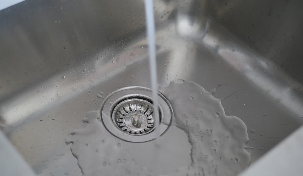 Water draining slowly around a kitchen sink strainer, indicating a possible clog