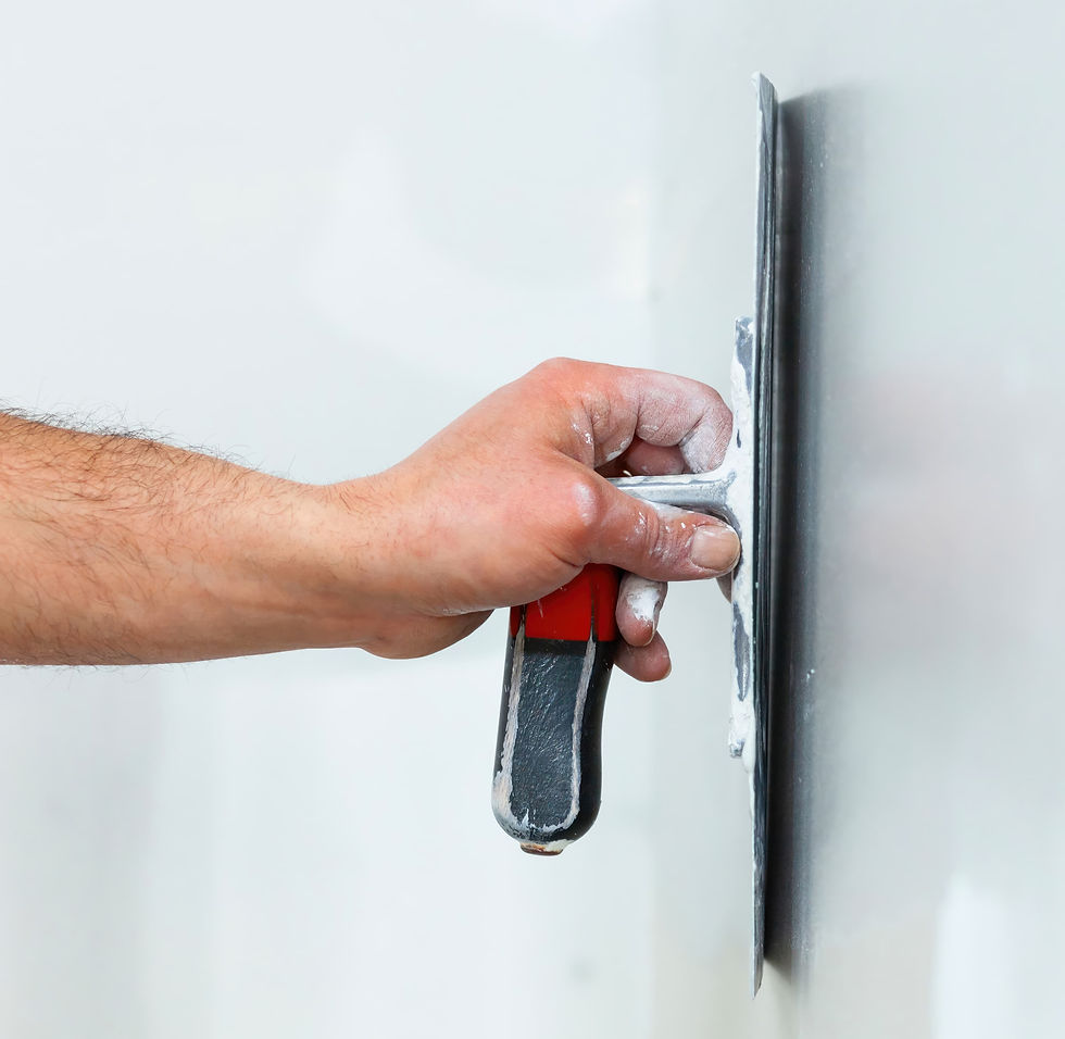 Close-up of hand smoothing wall with putty knife — surface preparation before interior painting