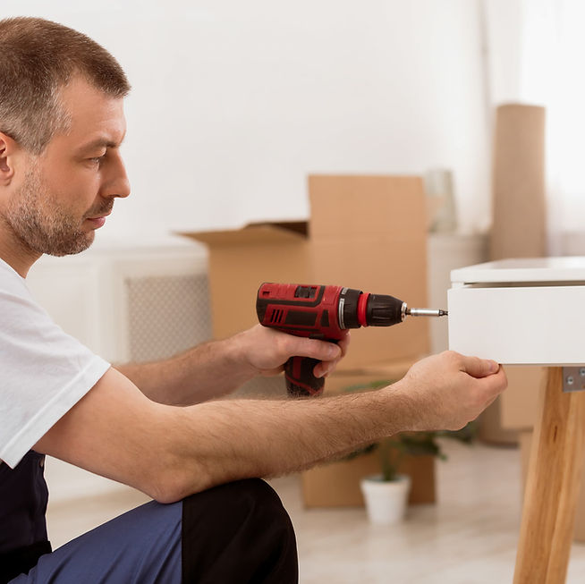 Furniture assembly — worker using drill on white cabinet in Arlington Heights home