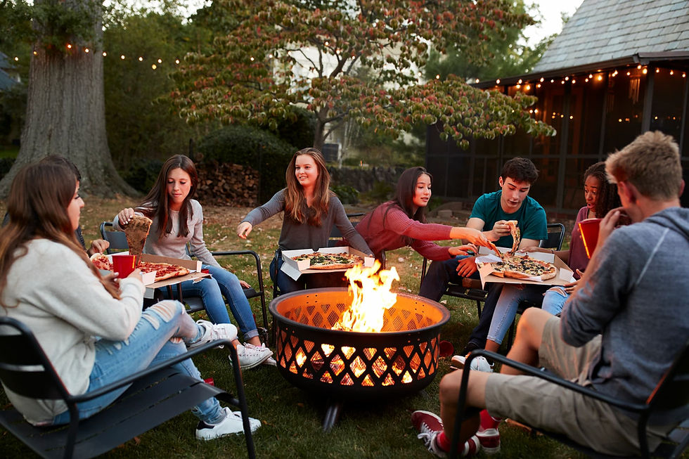 Backyard fire pit gathering in the Chicago suburbs with friends, pizza, and string lights on a fall evening.