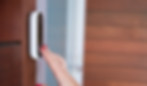 Person pressing a video doorbell mounted beside a front door.