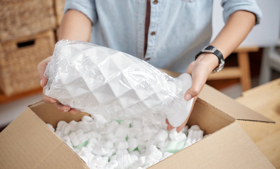 Person carefully wrapping a fragile white vase with packing materials and peanuts for a DIY move