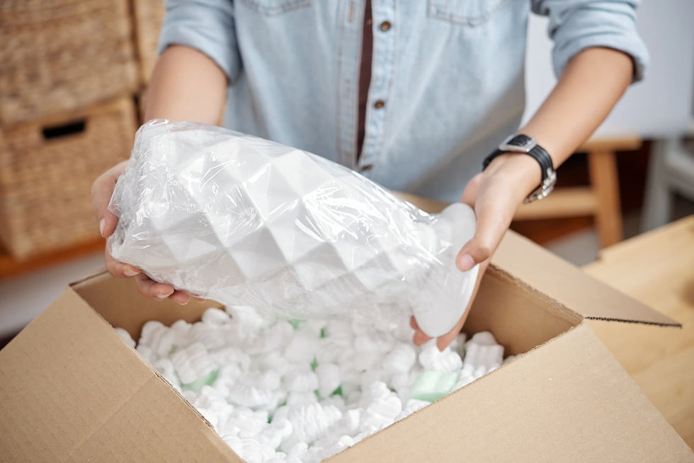 Person packing a fragile glass item with bubble wrap for a long-distance move
