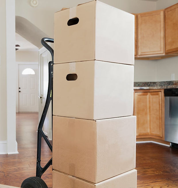 Hand truck stacked with cardboard boxes in a hallway, symbolizing the efficiency required for hourly-rate local moves