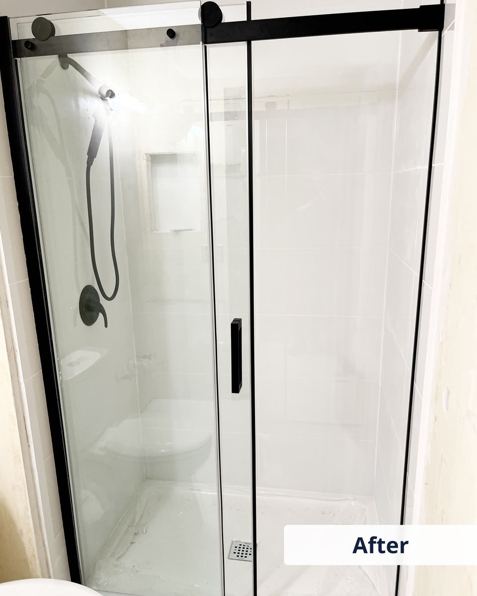 New frameless glass shower door with black trim after full bathroom upgrade