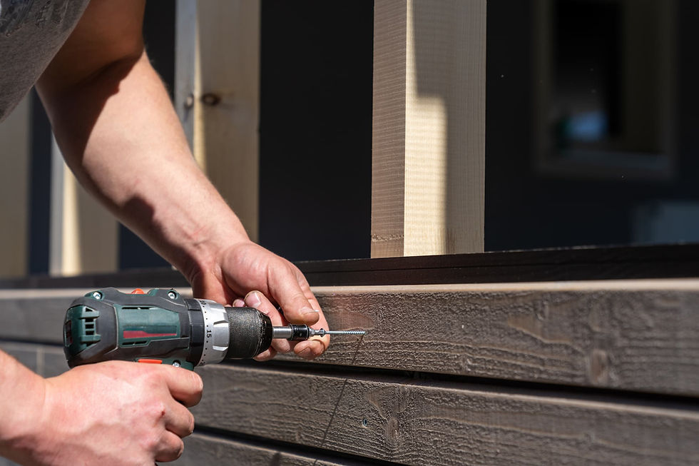 Securing a wooden porch railing with a drill as part of fall home maintenance.