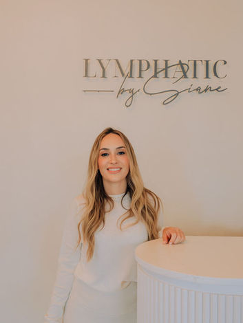 iane welcoming guests at the reception desk with the spa logo on the wall behind her.