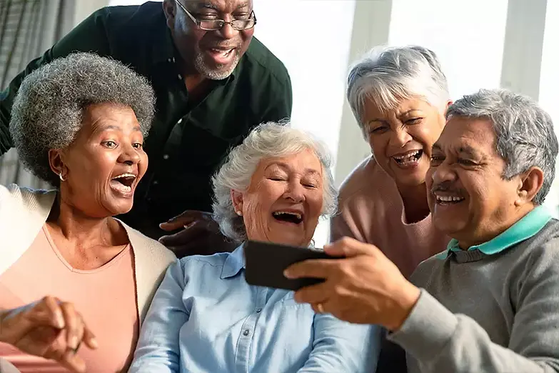 five-happy-diverse-senior-friends-sitting-on-sofa-and-looking-at-smartphone.webp