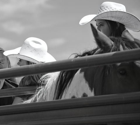 Cowboys and cowgirls watching, wearing hats, and observing the scene; Western Cowboy Chronicles.
