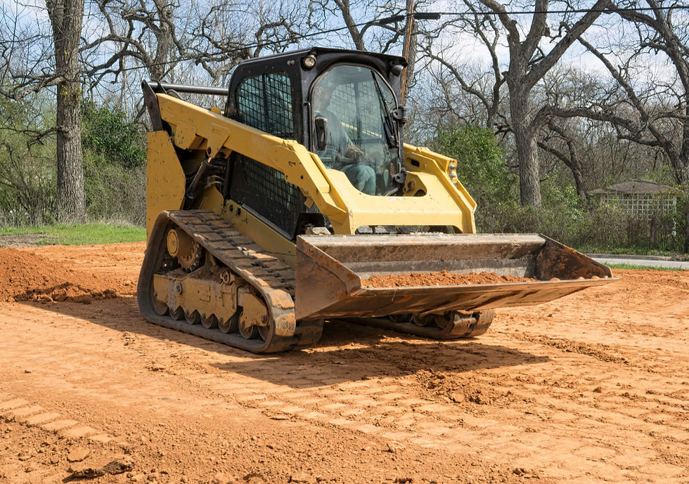 Yellow compact track loader moving red dirt on clear day.