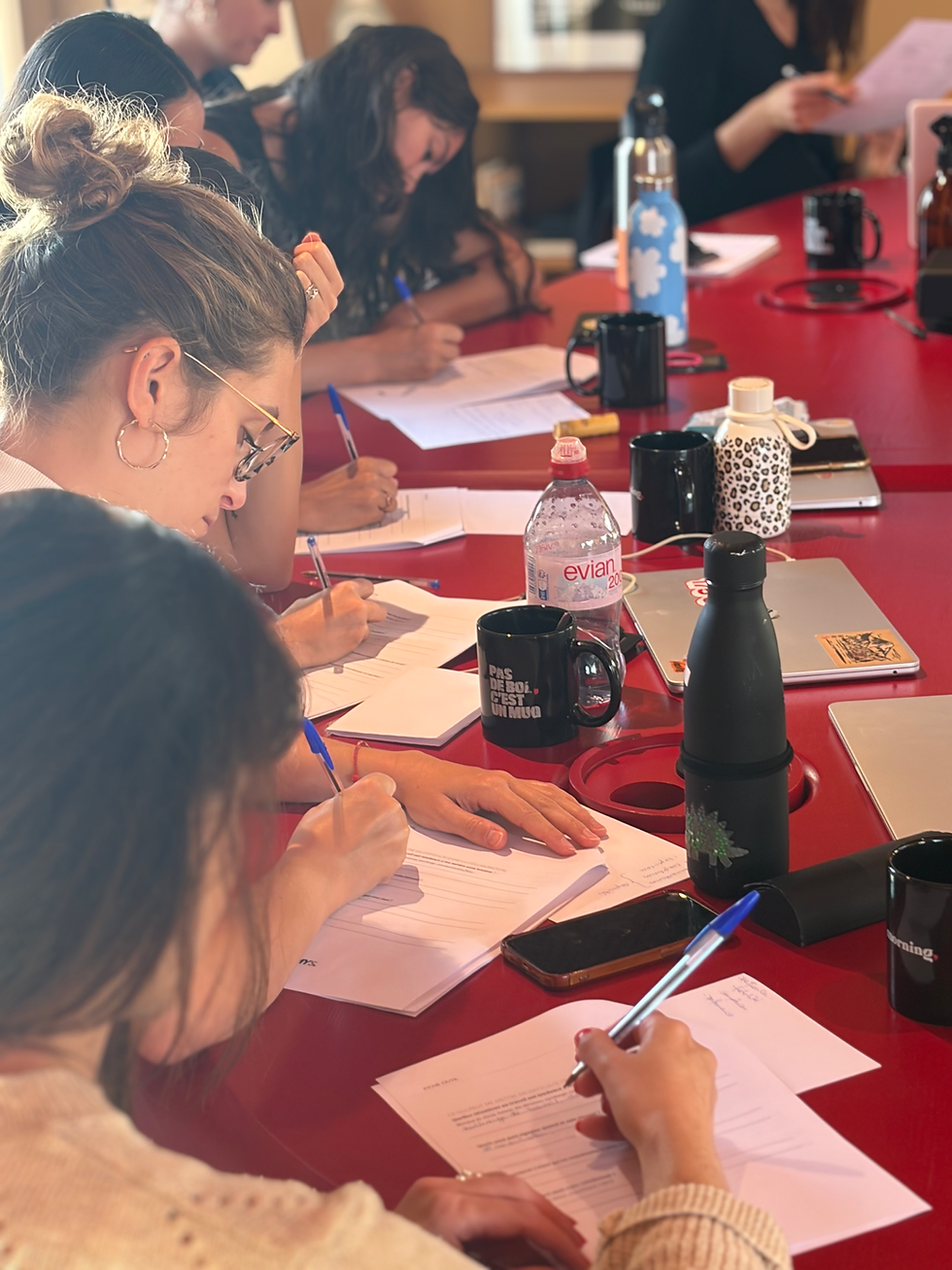 Participants en formation prenant des notes sur une table rouge.