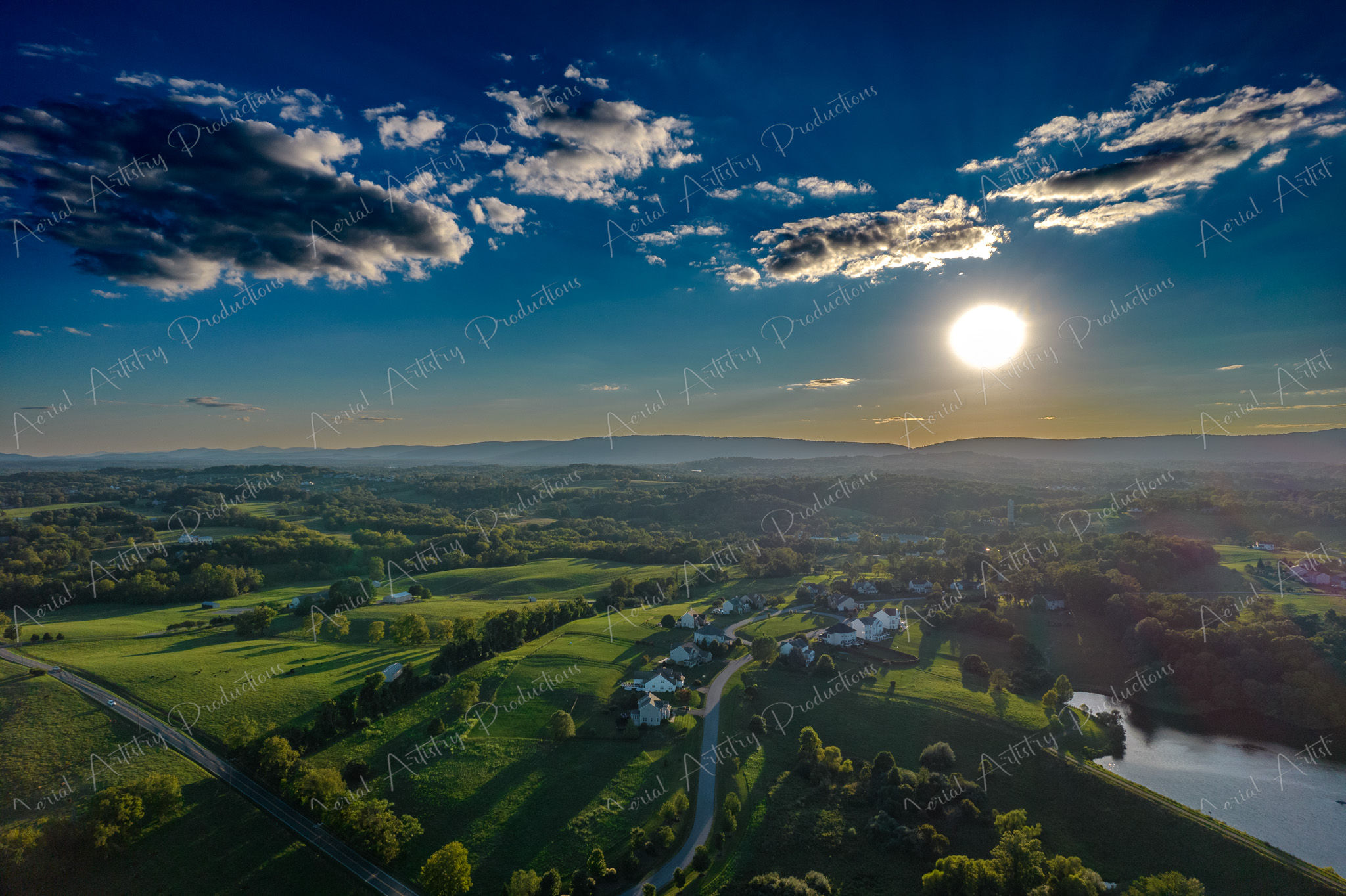 Aerial Sunset Over Countryside with Rolling Hills and Farmlands