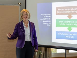 Frau steht und hält Vortrag vor Leinwand 